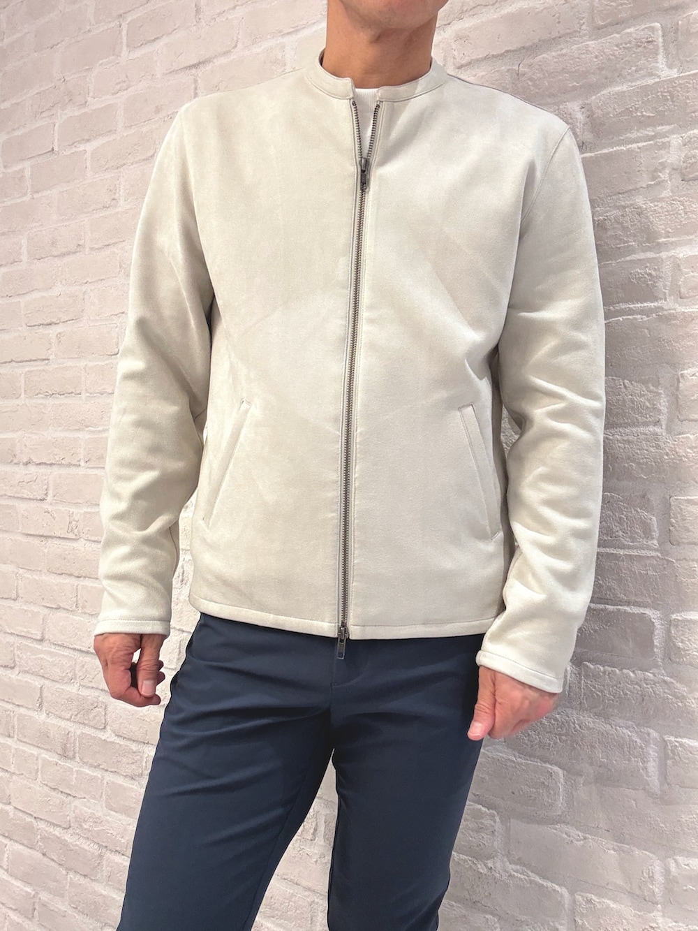 ベージュ系のライダースジャケット、ホワイト系のTシャツ/カットソー、ブルー系のスラックスを着用したメンズの秋コーディネートの3枚目の写真