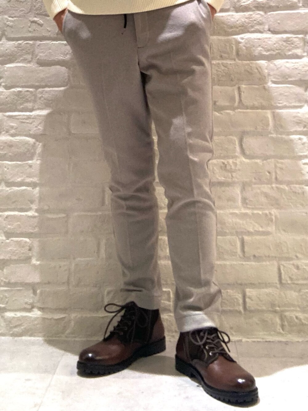 ホワイト系のニット/セーター、ベージュ系のスラックスを着用したメンズの冬コーディネートの3枚目の写真