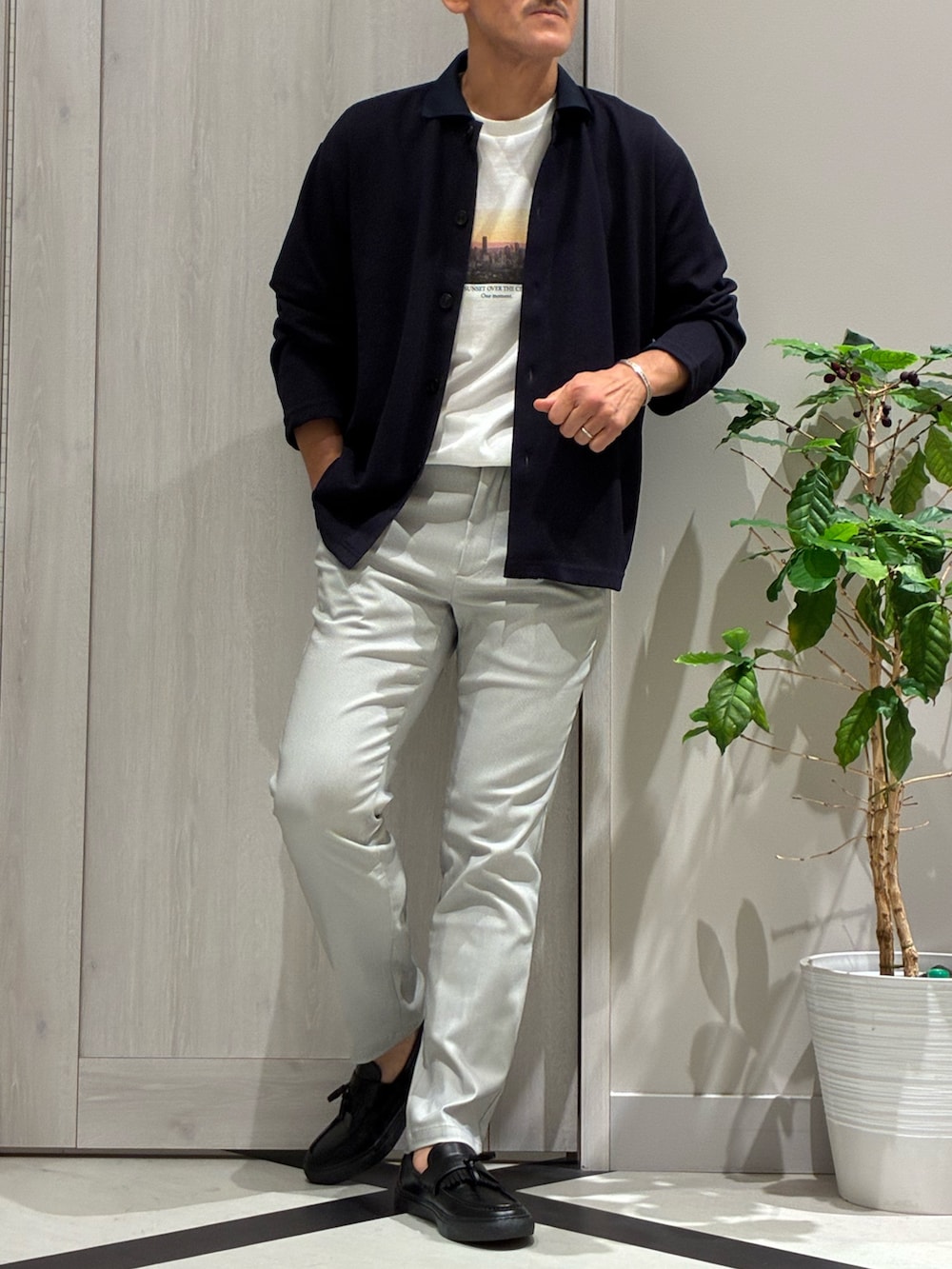 ブルー系のカーディガン/ボレロ、ホワイト系のTシャツ/カットソー、ベージュ系のスラックスを着用したメンズの秋コーディネートの2枚目の写真