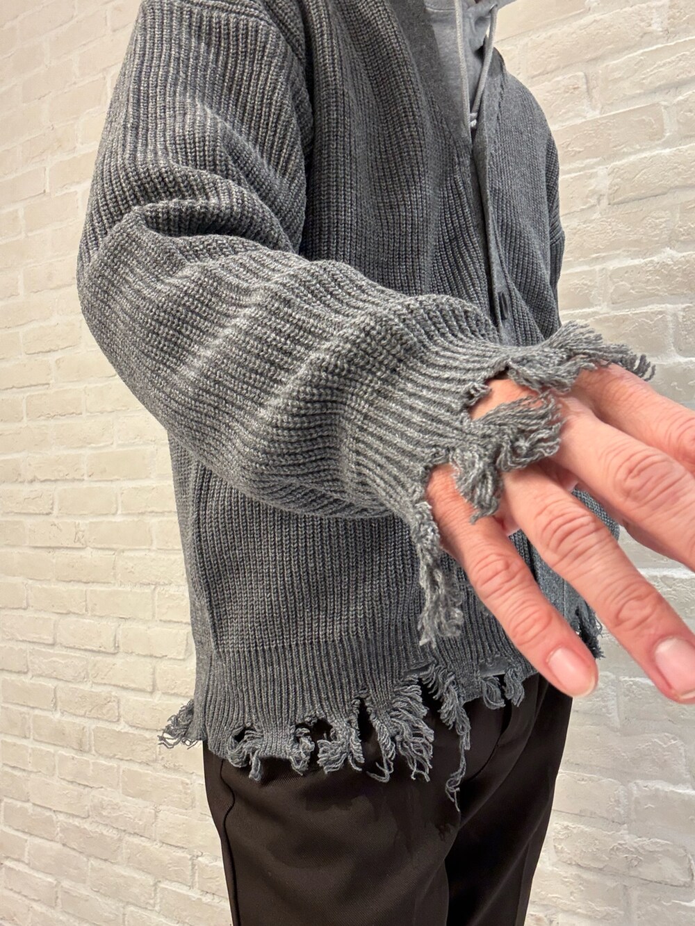 グレー系のカーディガン/ボレロ、グレー系のパーカー、ブラウン系のスラックスを着用したメンズの秋コーディネートの5枚目の写真