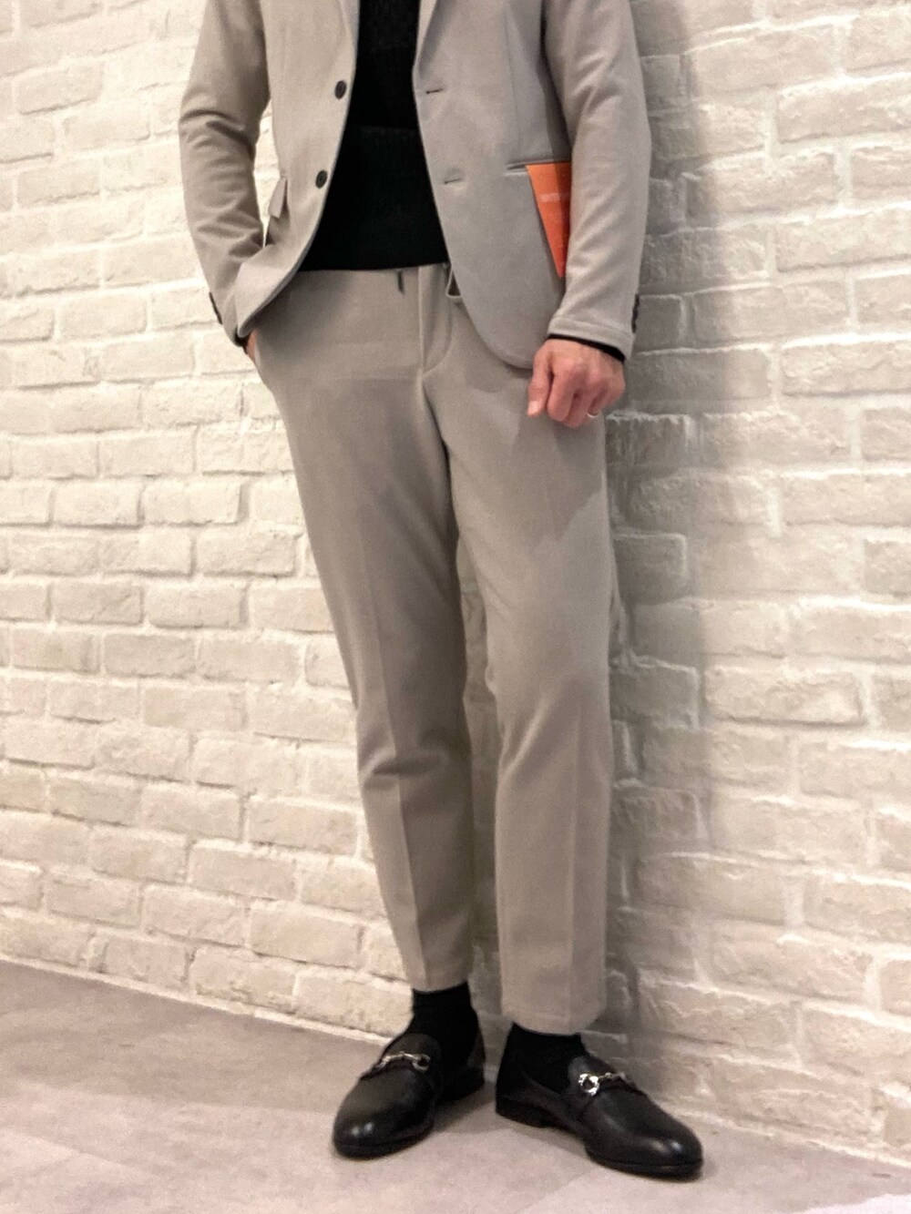 ベージュ系のセットアップ、ベージュ系のテーラードジャケット、ブラック系のニット/セーターを着用したメンズの冬コーディネートの3枚目の写真