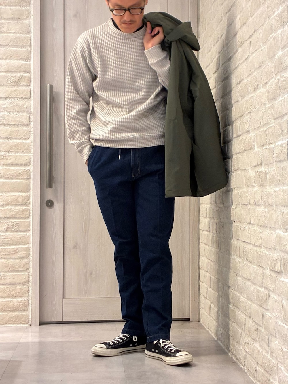 グリーン系のブルゾン、ベージュ系のTシャツ/カットソー、ブルー系のデニムパンツを着用したメンズの冬コーディネートの3枚目の写真