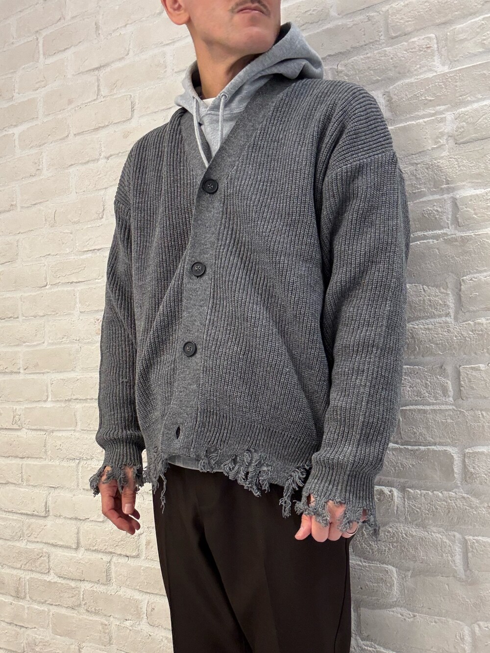 グレー系のカーディガン/ボレロ、グレー系のパーカー、ブラウン系のスラックスを着用したメンズの秋コーディネートの4枚目の写真