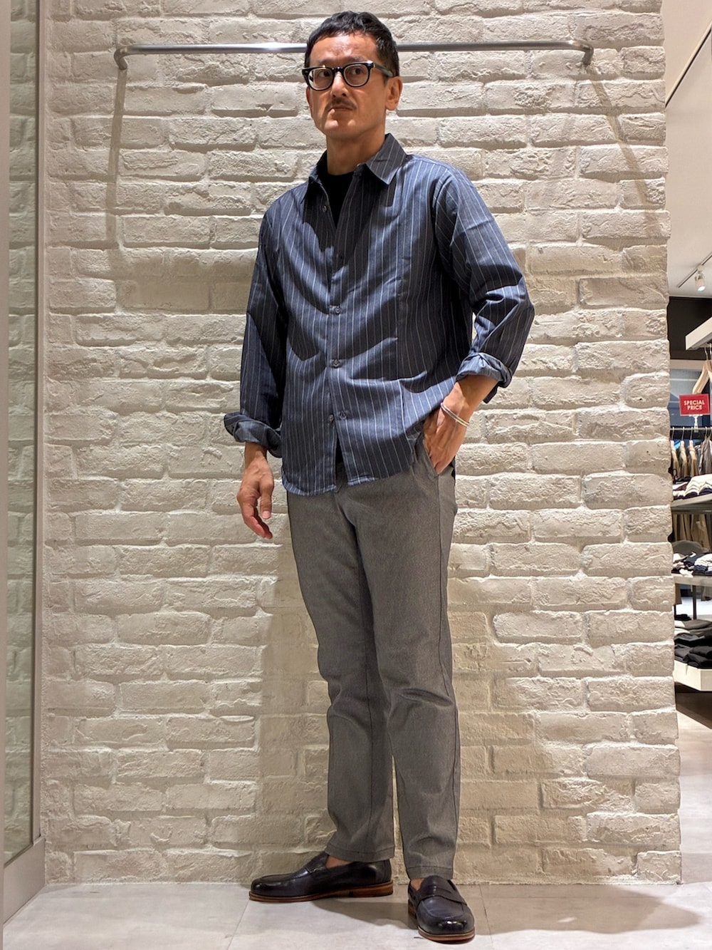 ブルー系のシャツ/ブラウス、ブルー系のTシャツ/カットソー、グレー系のスラックスを着用したメンズの秋コーディネートの5枚目の写真