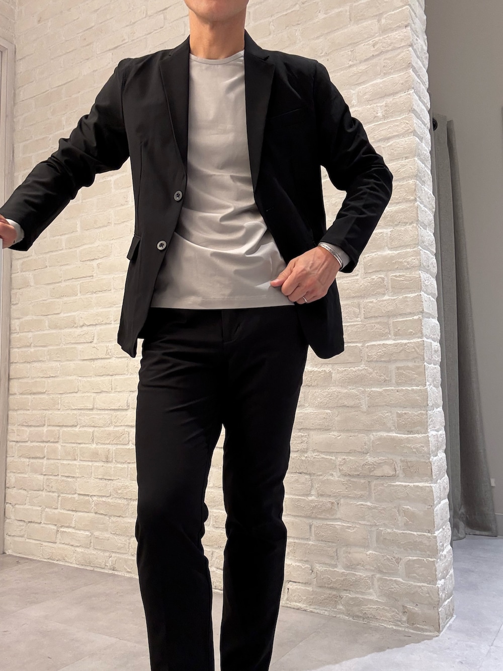 ベージュ系のTシャツ/カットソー、ブラック系のテーラードジャケット、ブラック系のセットアップを着用したメンズの秋コーディネートの2枚目の写真