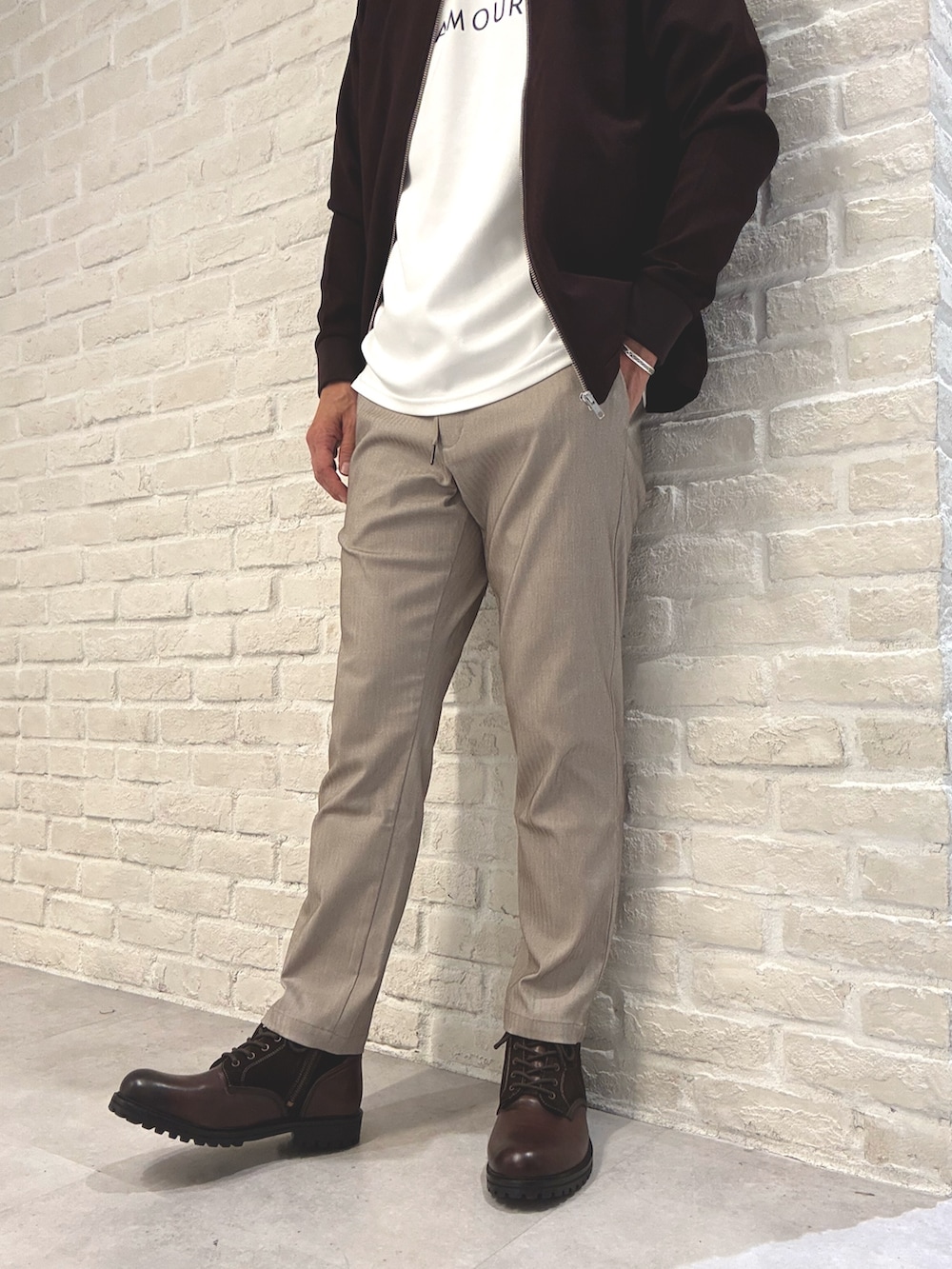 レッド系のブルゾン、ホワイト系のTシャツ/カットソー、ベージュ系のスラックスを着用したメンズの秋コーディネートの4枚目の写真