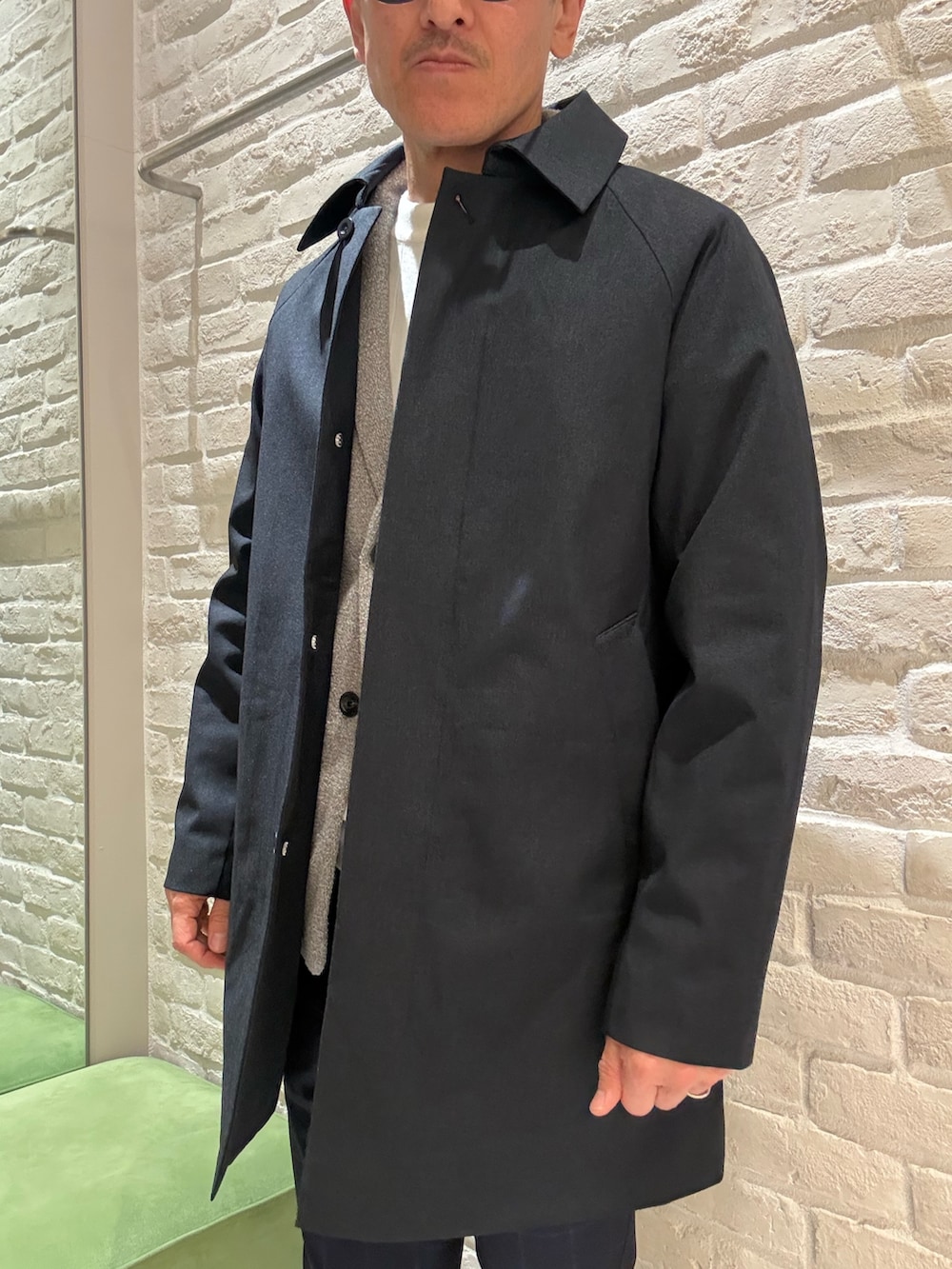 ブルー系のステンカラーコート、ブラウン系のブルゾン、ホワイト系のニット/セーターを着用したメンズの春コーディネートの4枚目の写真