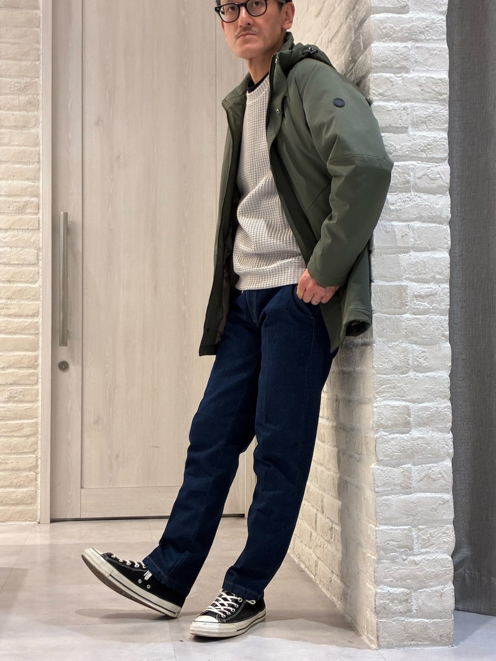 グリーン系のブルゾン、ベージュ系のTシャツ/カットソー、ブルー系のデニムパンツを着用したメンズの冬コーディネートの2枚目の写真