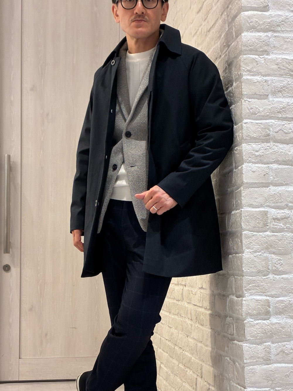 ブルー系のステンカラーコート、ブラウン系のブルゾン、ホワイト系のニット/セーターを着用したメンズの春コーディネートの3枚目の写真