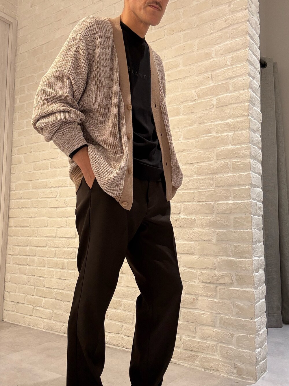 ベージュ系のカーディガン/ボレロ、ブラック系のTシャツ/カットソー、ブラウン系のスラックスを着用したメンズの秋コーディネートの2枚目の写真