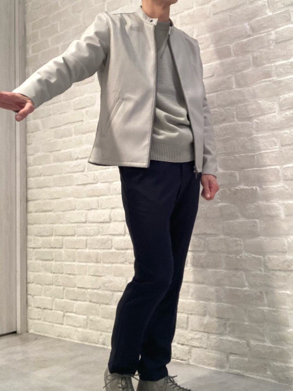 グレー系のライダースジャケット、グリーン系のニット/セーター、ブルー系のスラックスを着用したメンズの春コーディネートの3枚目の写真