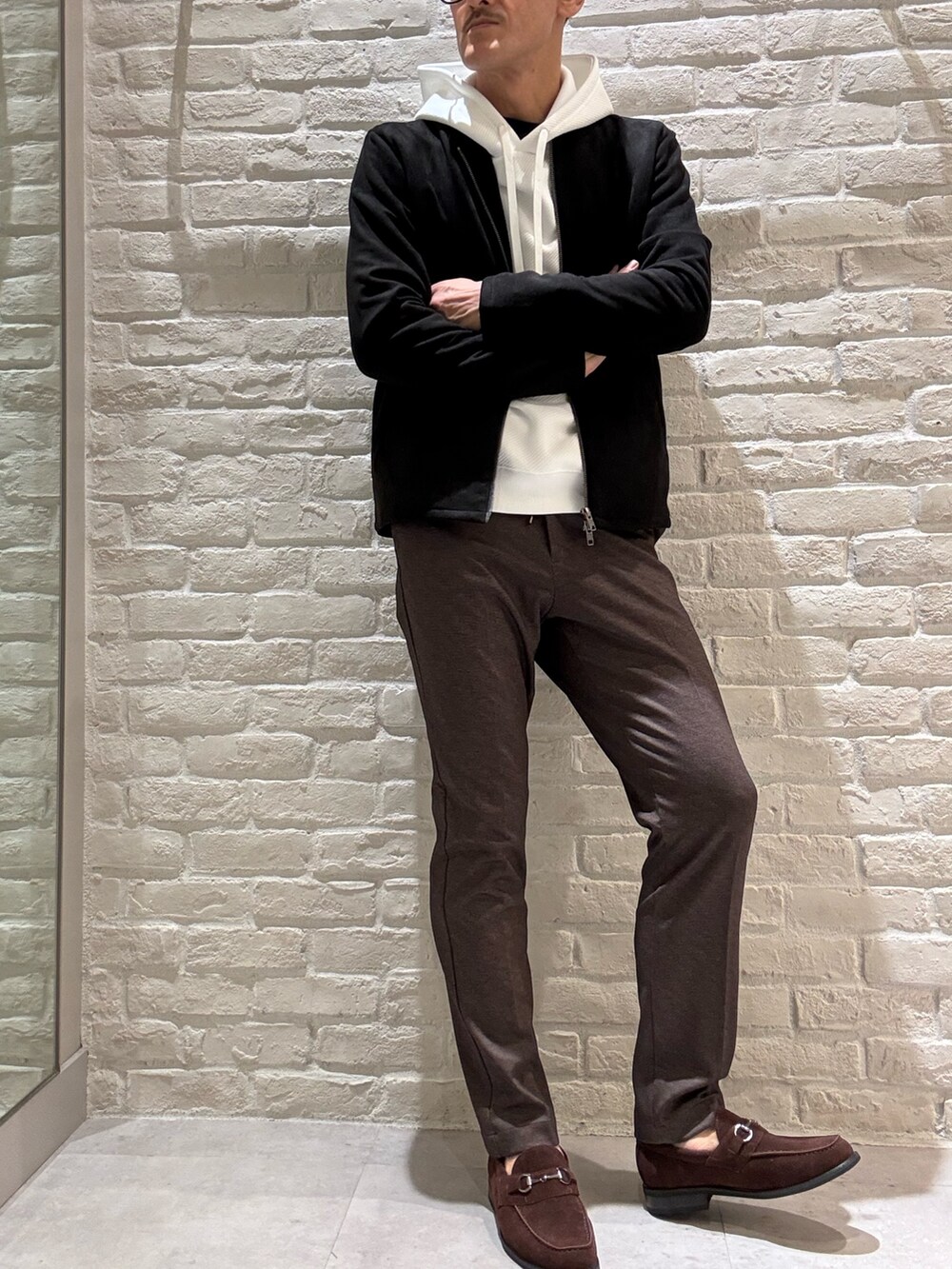 ブラック系のライダースジャケット、ホワイト系のパーカー、その他のスラックスを着用したメンズの秋コーディネートの2枚目の写真