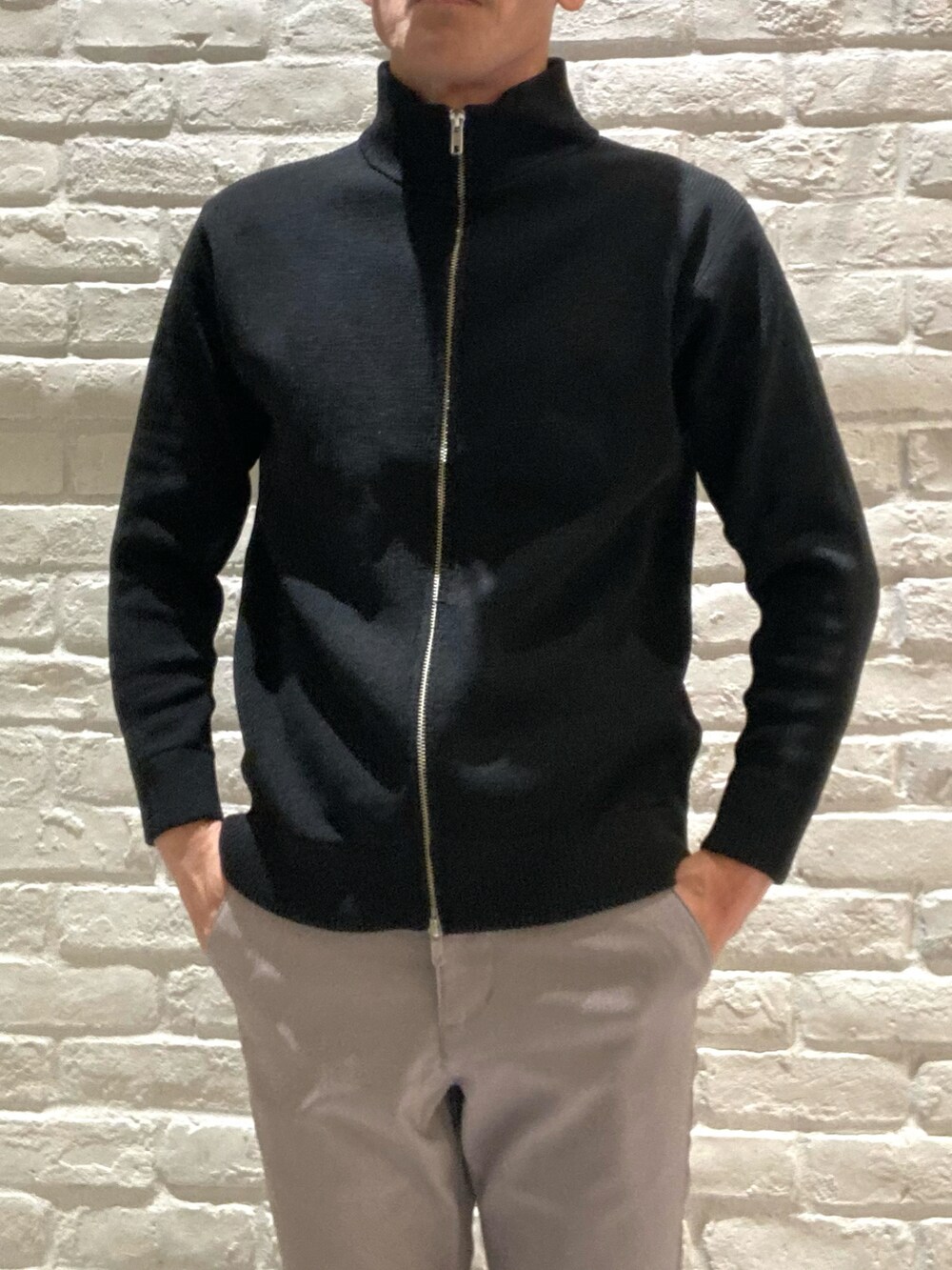 ベージュ系のステンカラーコート、ブラック系のニット/セーター、ブラック系のカーディガン/ボレロを着用したメンズの冬コーディネートの3枚目の写真