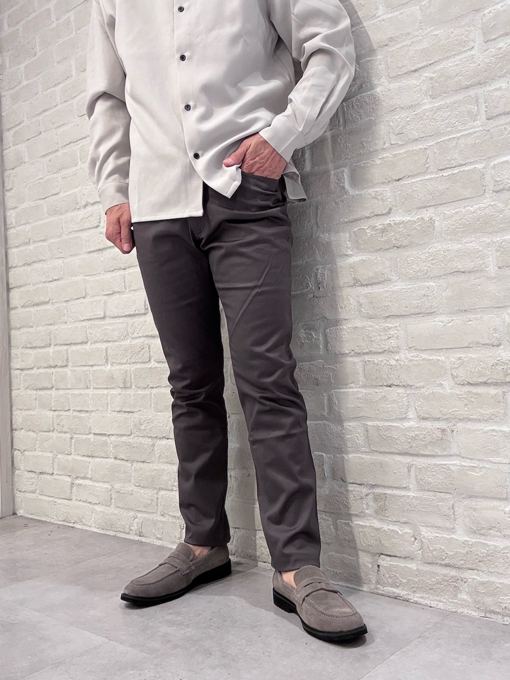 グレー系のチノパンツ、ブラック系のニット/セーター、ベージュ系のシャツ/ブラウスを着用したメンズの秋コーディネートの6枚目の写真