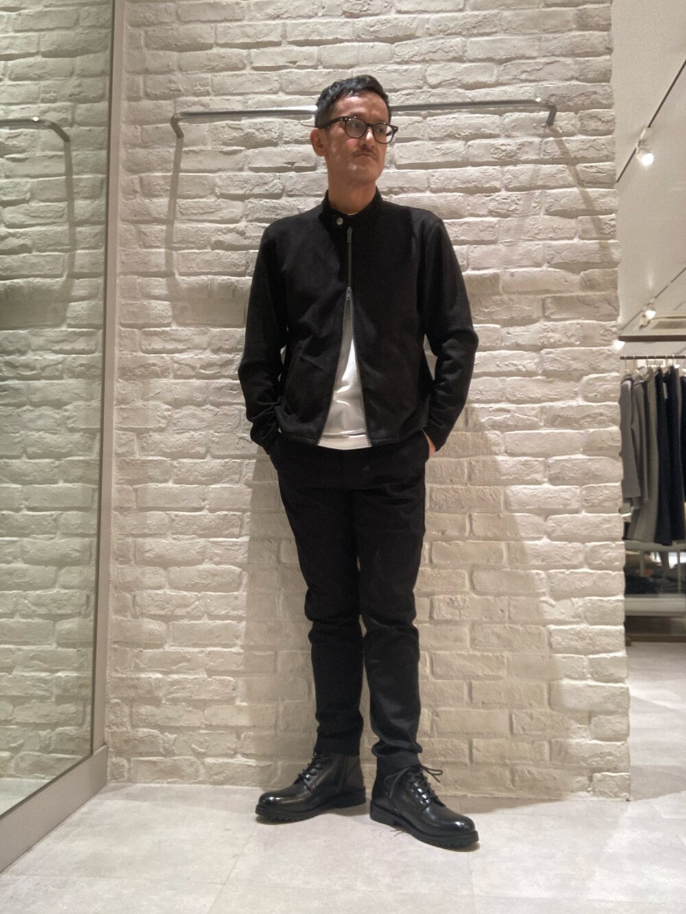 ブラック系のブルゾン、ホワイト系のTシャツ/カットソー、ブラック系のチノパンツを着用したメンズの秋コーディネートの4枚目の写真