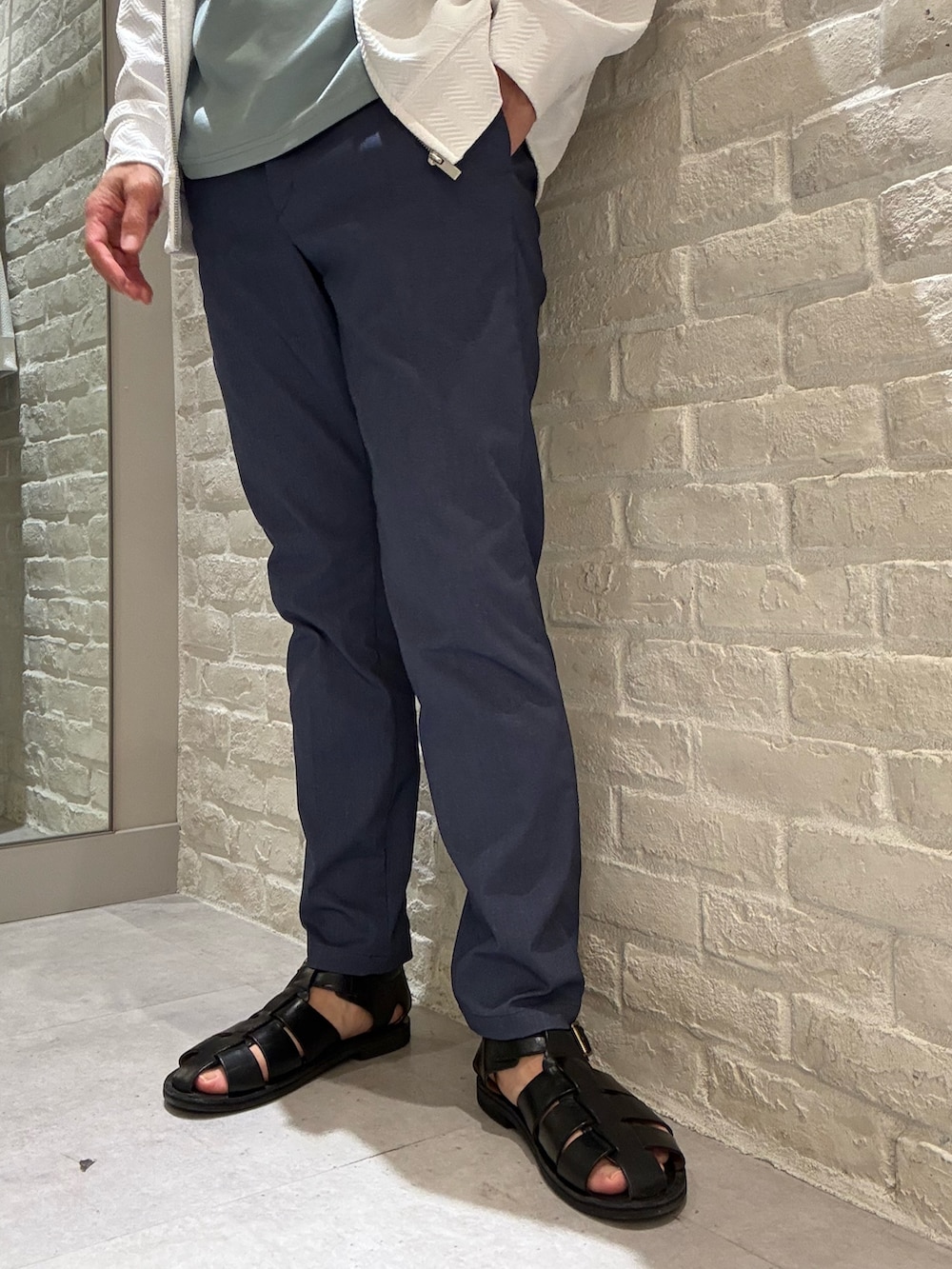 ホワイト系のパーカー、グリーン系のTシャツ/カットソー、ブルー系のスラックスを着用したメンズの春コーディネートの4枚目の写真