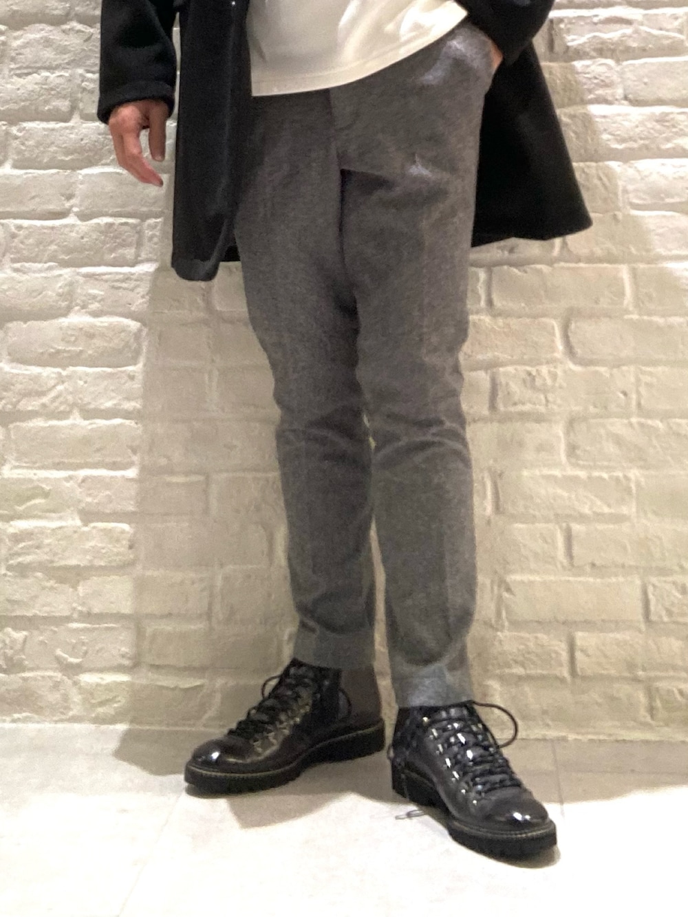 ブラック系のチェスターコート、ホワイト系のパーカー、グレー系のスラックスを着用したメンズの秋コーディネートの2枚目の写真