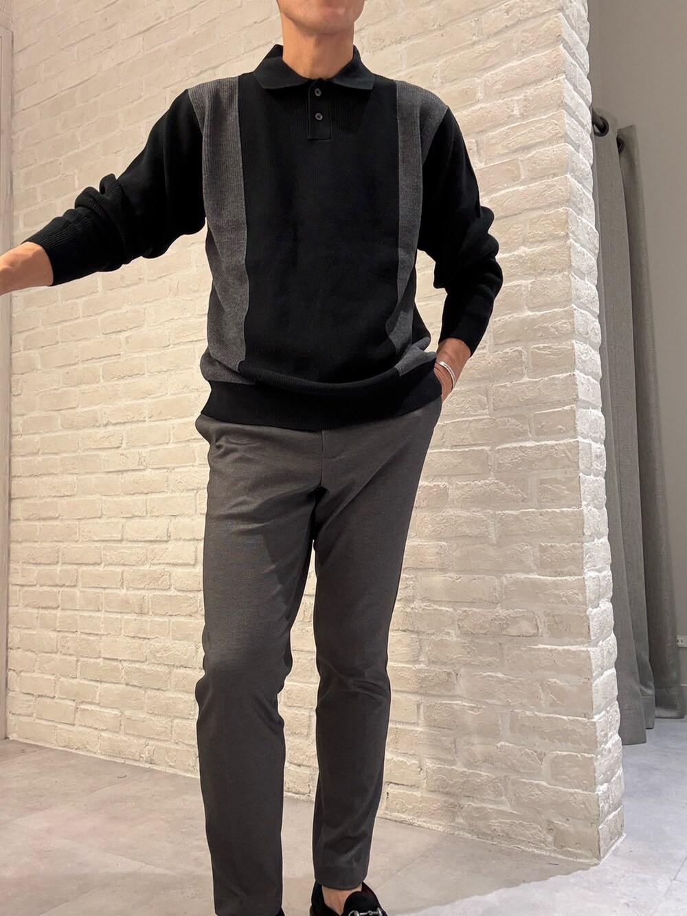 ブラック系のニット/セーター、グレー系のスラックス、ブラック系のトートバッグを着用したメンズの秋コーディネートの2枚目の写真