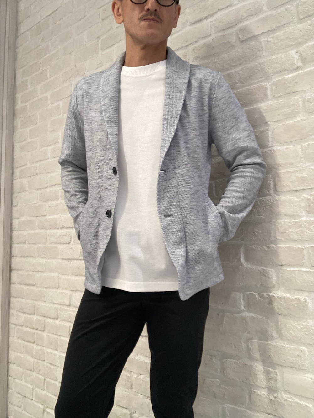 グレー系のブルゾン、ホワイト系のTシャツ/カットソー、ブラック系のスラックスを着用したメンズの夏コーディネートの2枚目の写真