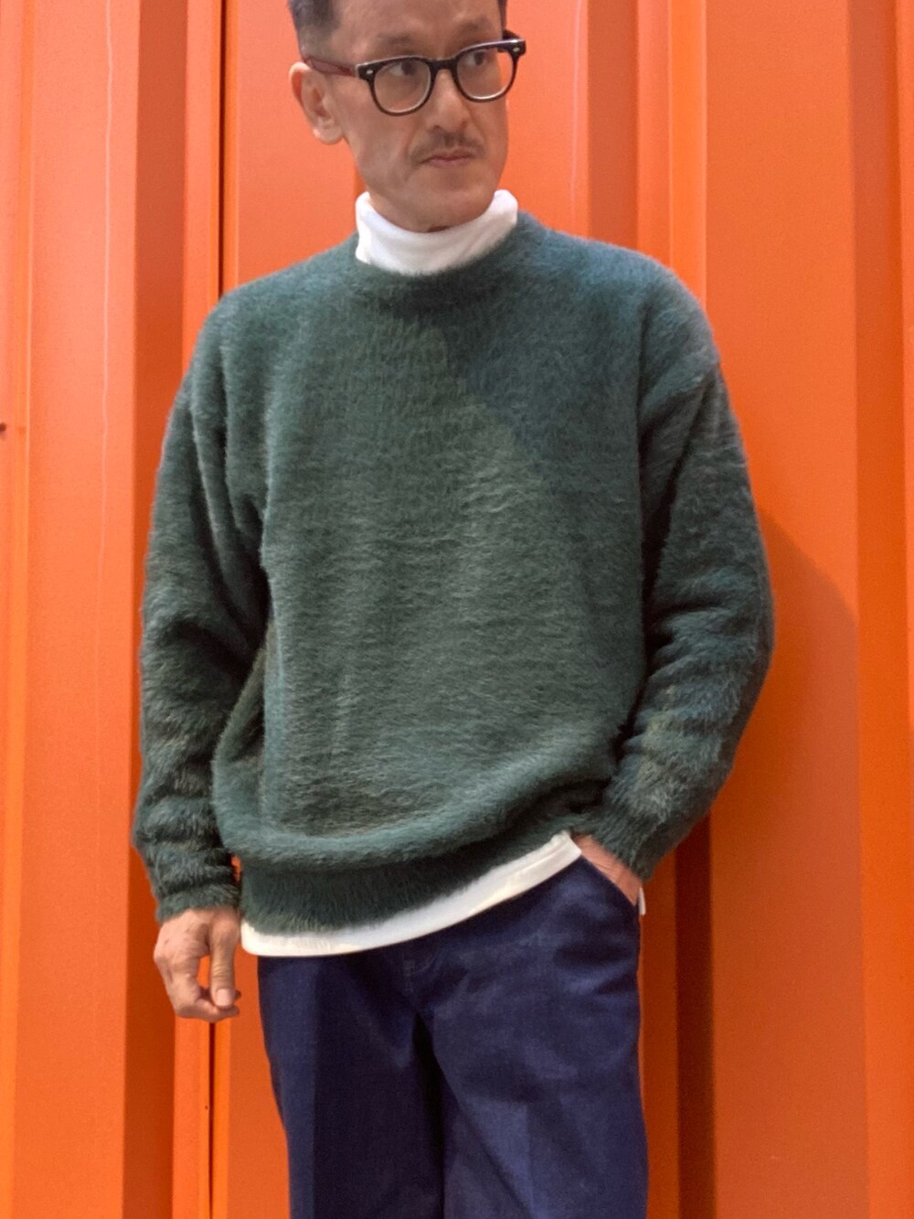 ホワイト系のTシャツ/カットソー、グリーン系のニット/セーター、ブラック系のスニーカーを着用したメンズの冬コーディネートの2枚目の写真