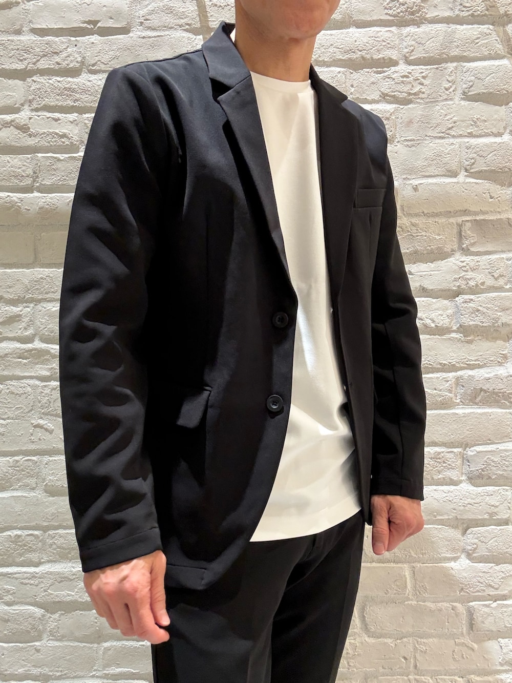 ブラック系のセットアップ、ブラック系のテーラードジャケット、ホワイト系のTシャツ/カットソーを着用したメンズの春コーディネートの2枚目の写真