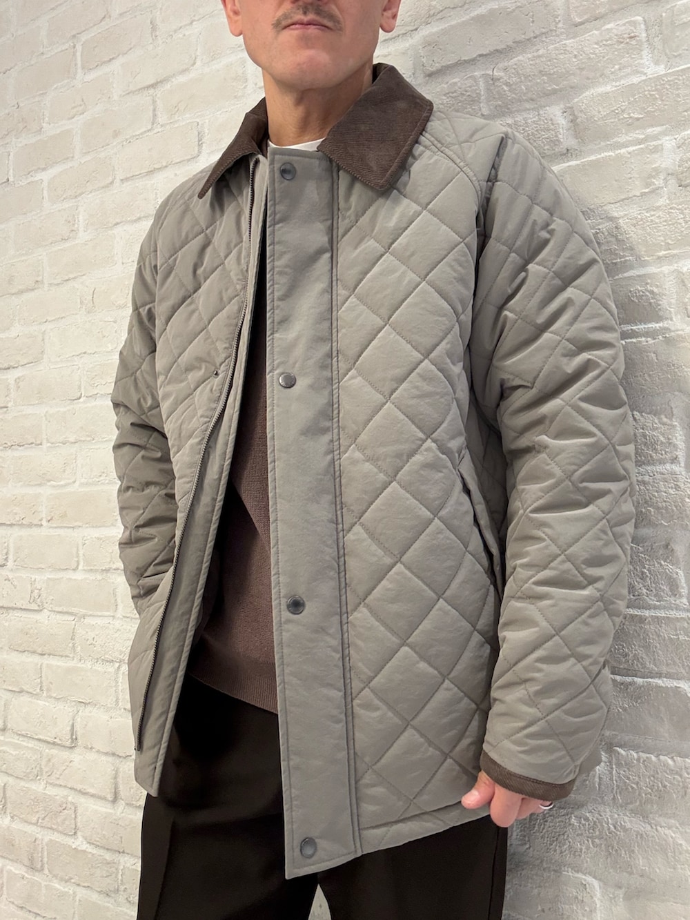 ブラウン系のブルゾン、ブラウン系のスラックス、ベージュ系のニット/セーターを着用したメンズの冬コーディネートの2枚目の写真