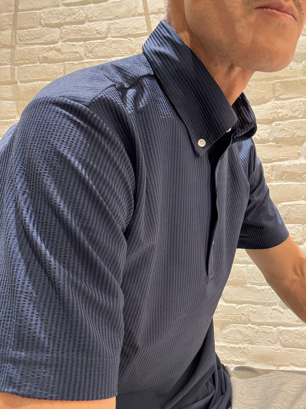 ブルー系のポロシャツ、グレー系のスラックス、ブラック系のトートバッグを着用したメンズの夏コーディネートの3枚目の写真