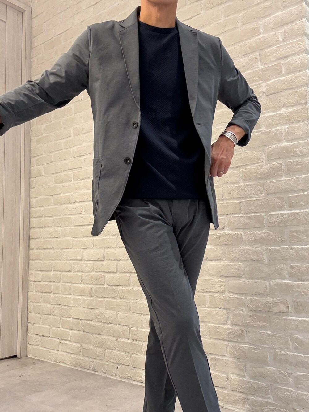 グレー系のテーラードジャケット、グレー系のスラックス、ブルー系のTシャツ/カットソーを着用したメンズの夏コーディネートの2枚目の写真