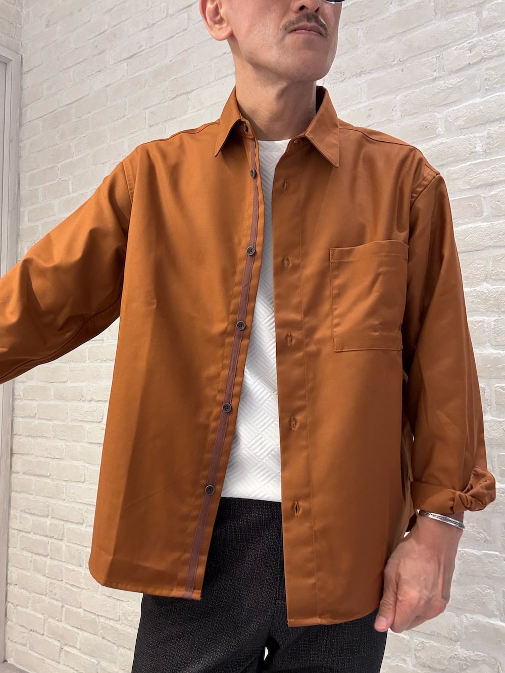オレンジ系のシャツ/ブラウス、ブラック系のスラックス、ホワイト系のTシャツ/カットソーを着用したメンズの秋コーディネートの3枚目の写真