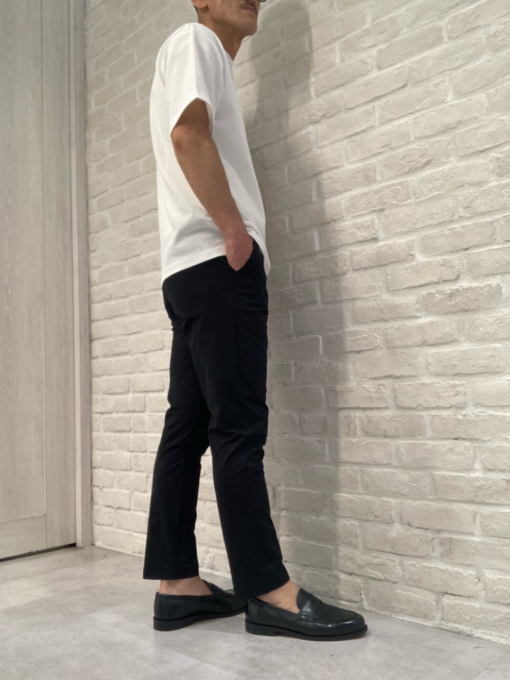 グレー系のブルゾン、ホワイト系のTシャツ/カットソー、ブラック系のスラックスを着用したメンズの夏コーディネートの4枚目の写真