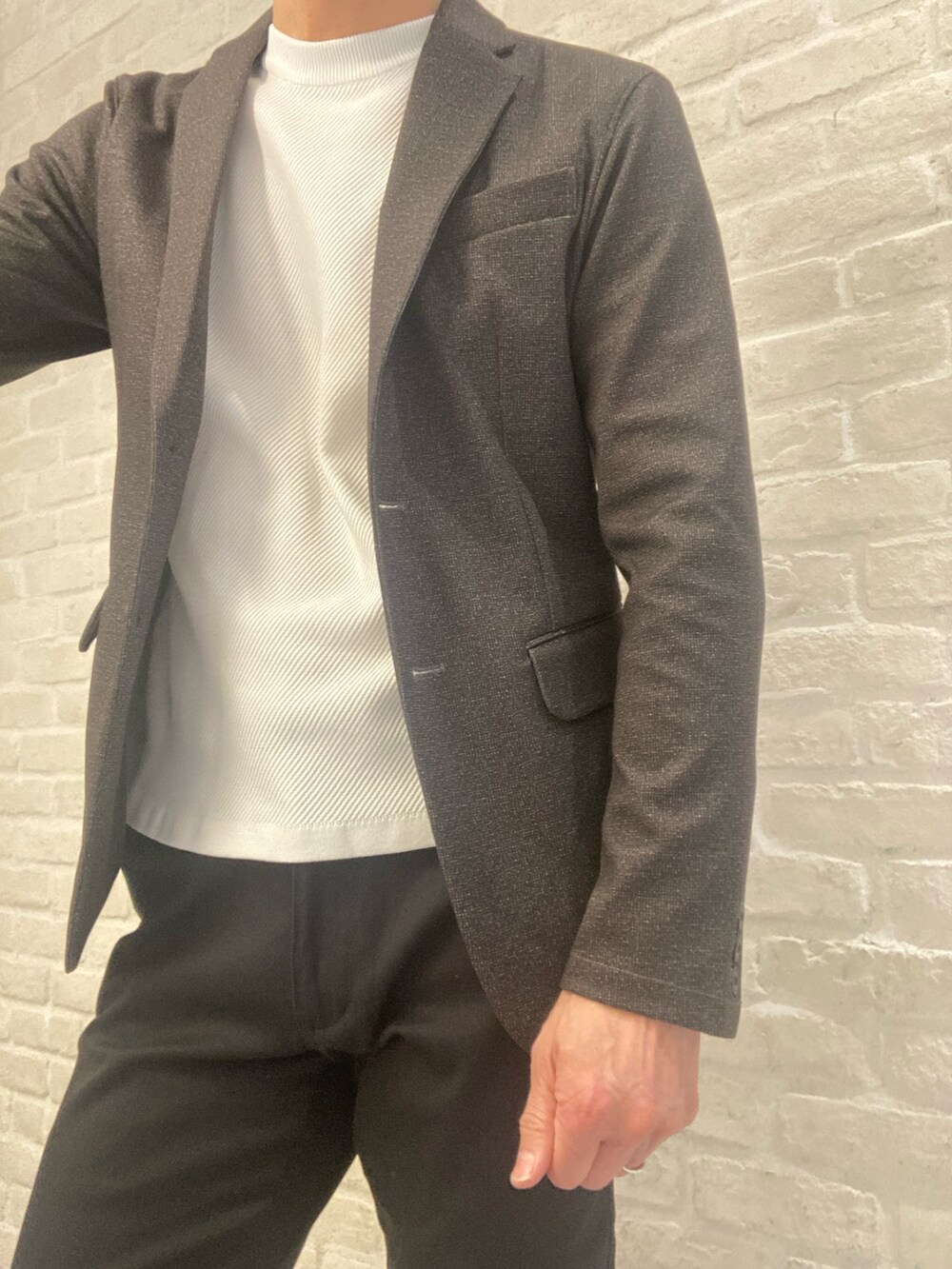 ブラウン系のテーラードジャケット、ブラック系のチノパンツ、ホワイト系のニット/セーターを着用したメンズの春コーディネートの4枚目の写真