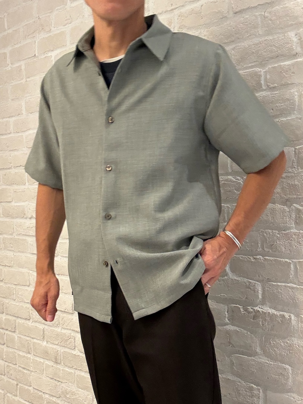 グリーン系のシャツ/ブラウス、ブラック系のTシャツ/カットソー、ブラウン系のスラックスを着用したメンズの夏コーディネートの3枚目の写真