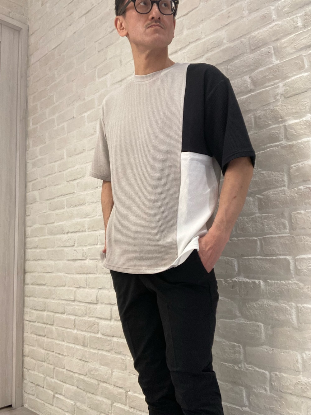 ブラック系のカーディガン/ボレロ、ベージュ系のTシャツ/カットソー、ブラック系のスラックスを着用したメンズの春コーディネートの2枚目の写真