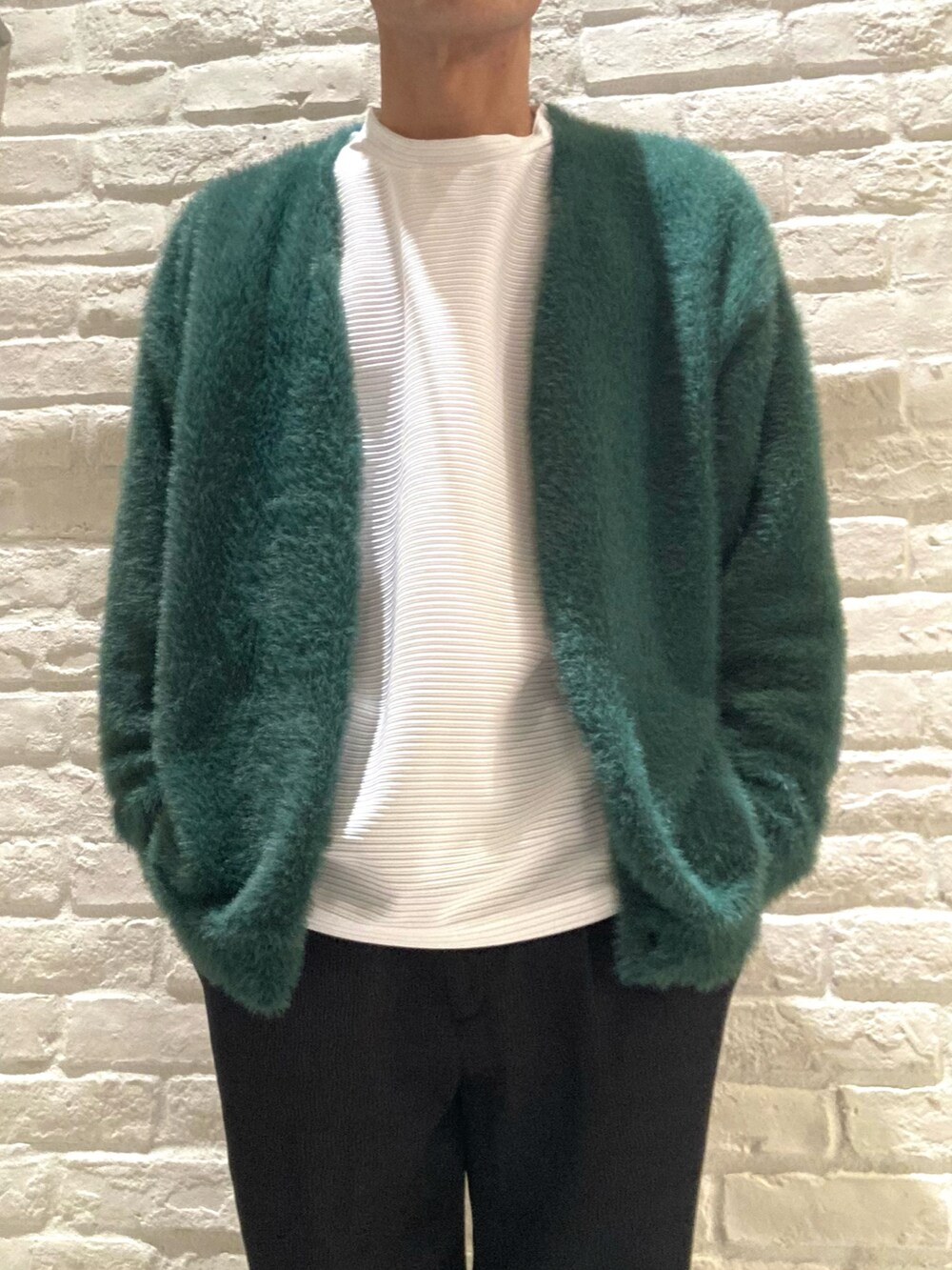 グリーン系のカーディガン/ボレロ、ホワイト系のTシャツ/カットソー、ブラック系のスラックスを着用したメンズの秋コーディネートの3枚目の写真