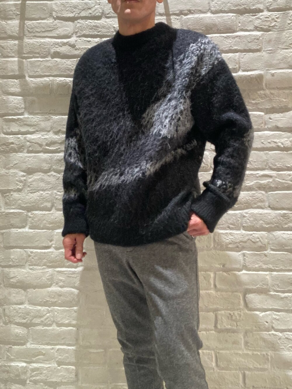 ブラック系のライダースジャケット、ブラック系のニット/セーター、グレー系のスラックスを着用したメンズの冬コーディネートの4枚目の写真