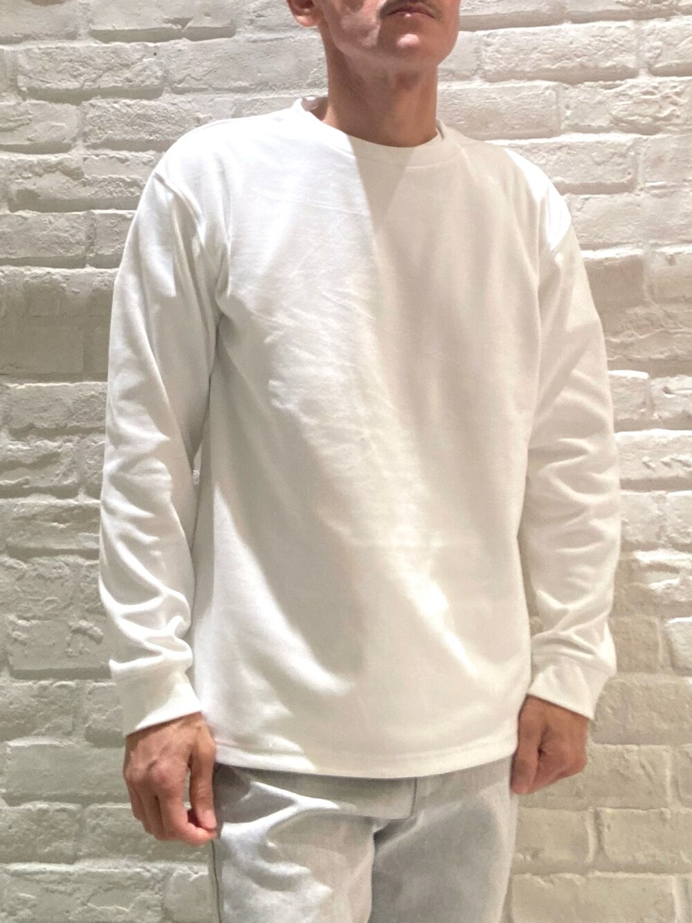 グレー系のダウンジャケット/コート、ホワイト系のTシャツ/カットソー、グレー系のその他パンツを着用したメンズの冬コーディネートの4枚目の写真