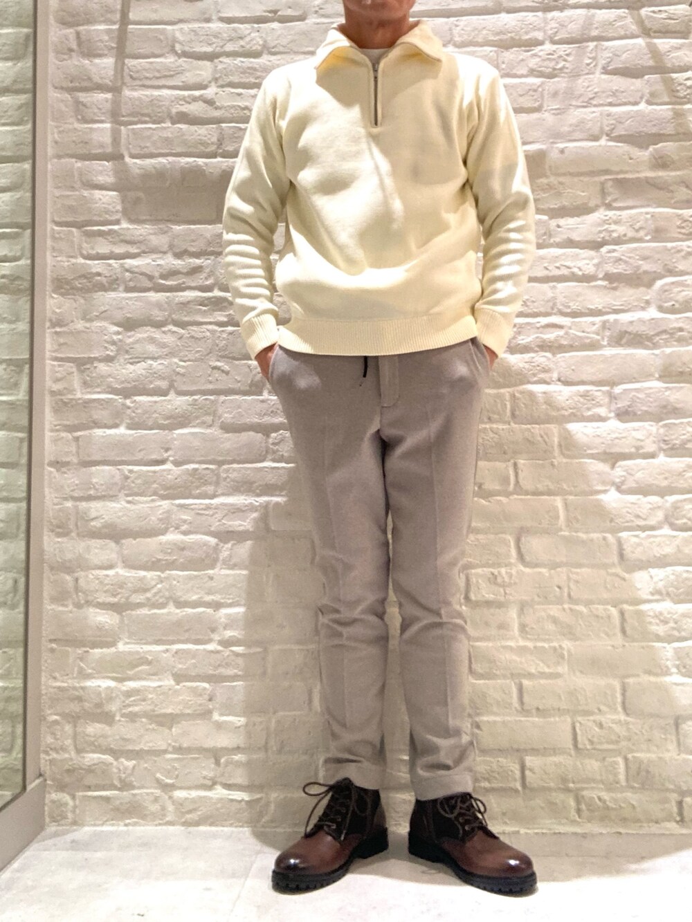 ホワイト系のニット/セーター、ベージュ系のスラックスを着用したメンズの冬コーディネートの2枚目の写真