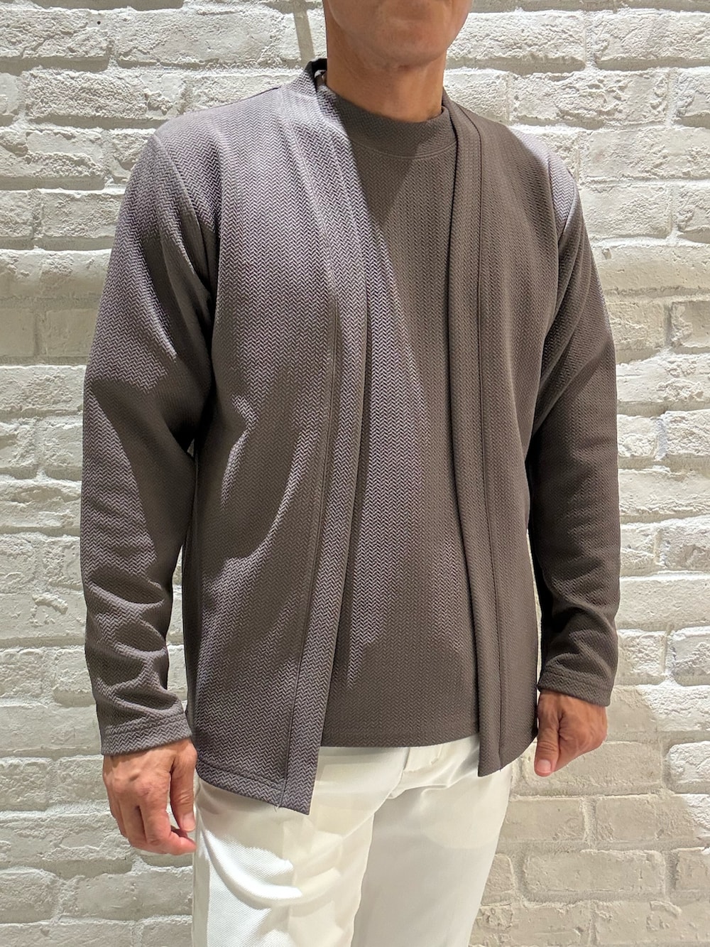 ブラウン系のカーディガン/ボレロ、ブラウン系のTシャツ/カットソー、ホワイト系のスラックスを着用したメンズの秋コーディネートの2枚目の写真