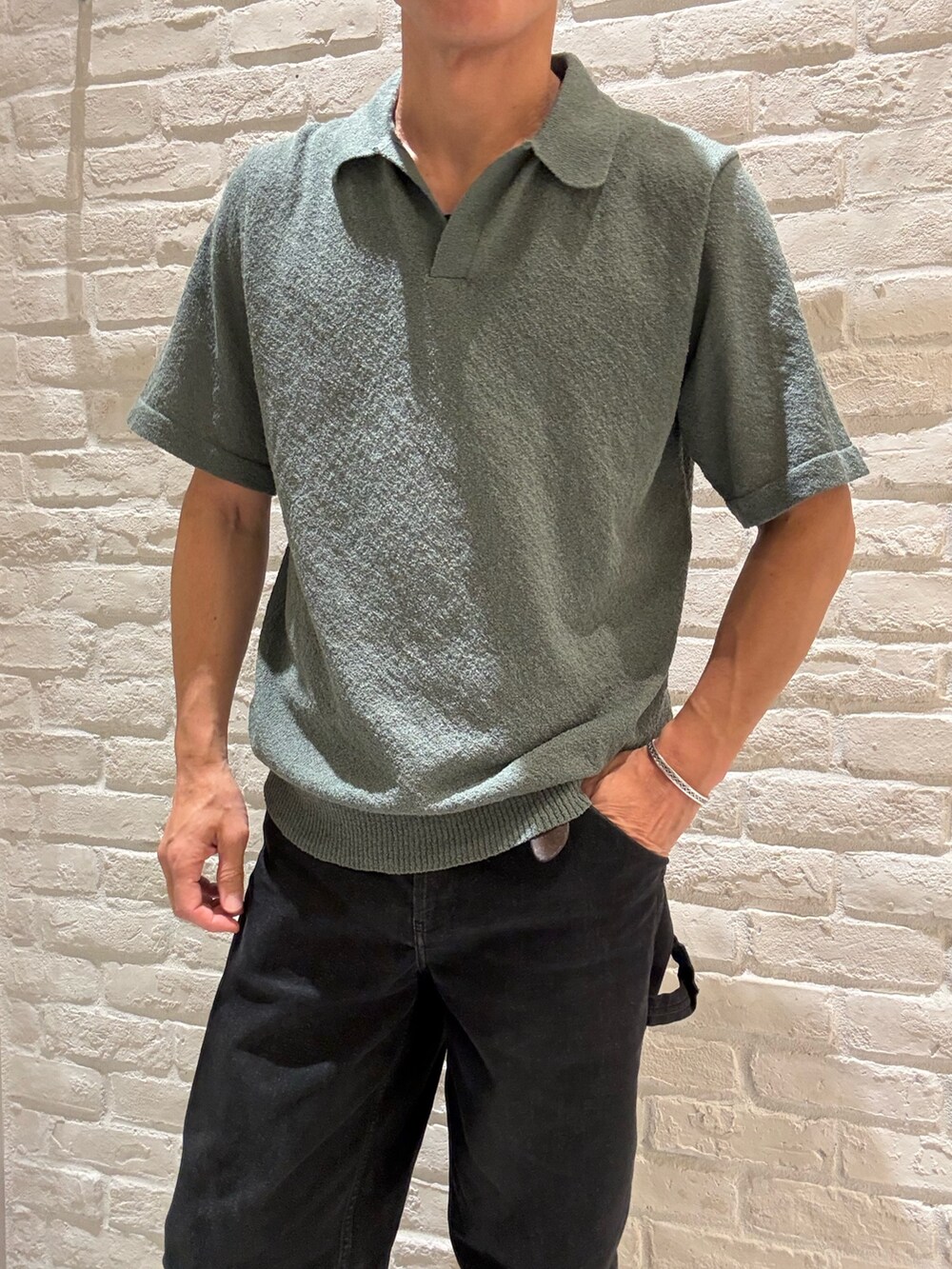 グリーン系のポロシャツ、ブラック系のTシャツ/カットソー、ベージュ系のキャップを着用したメンズの春コーディネートの2枚目の写真