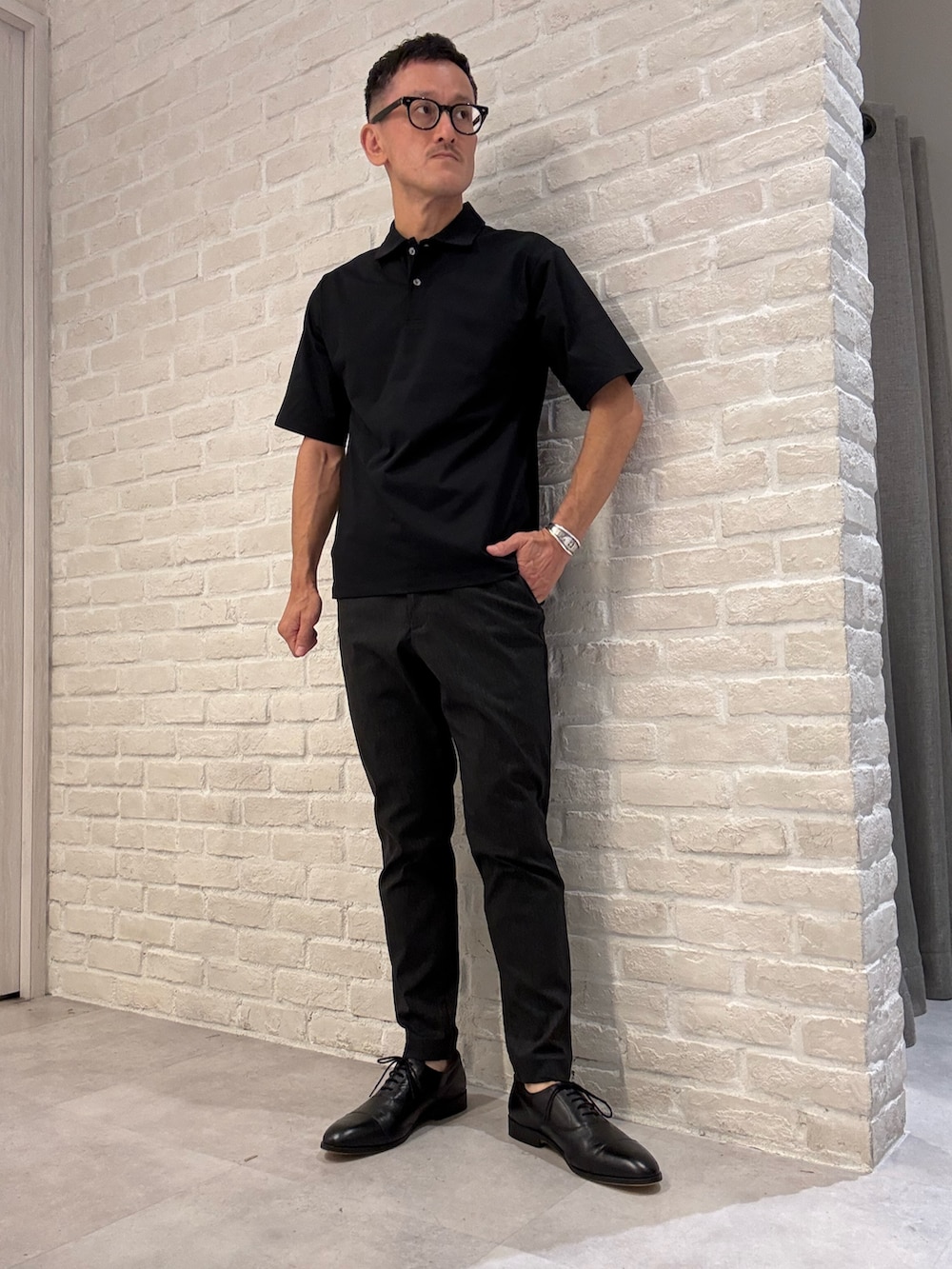 ブラック系のポロシャツ、ブラック系のスラックス、ブラック系のビジネスバッグを着用したメンズの夏コーディネートの3枚目の写真