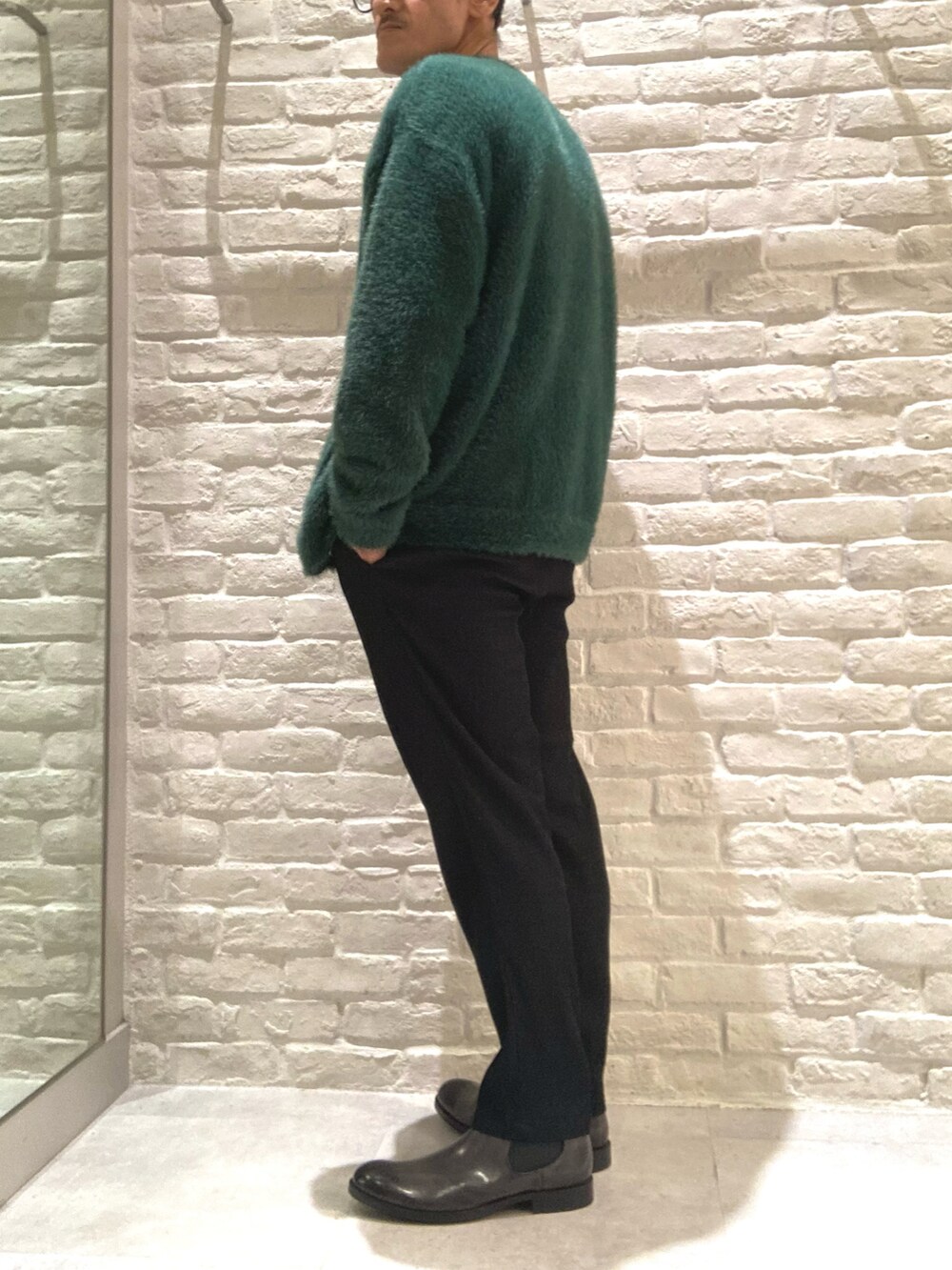 グリーン系のカーディガン/ボレロ、ホワイト系のTシャツ/カットソー、ブラック系のスラックスを着用したメンズの秋コーディネートの5枚目の写真