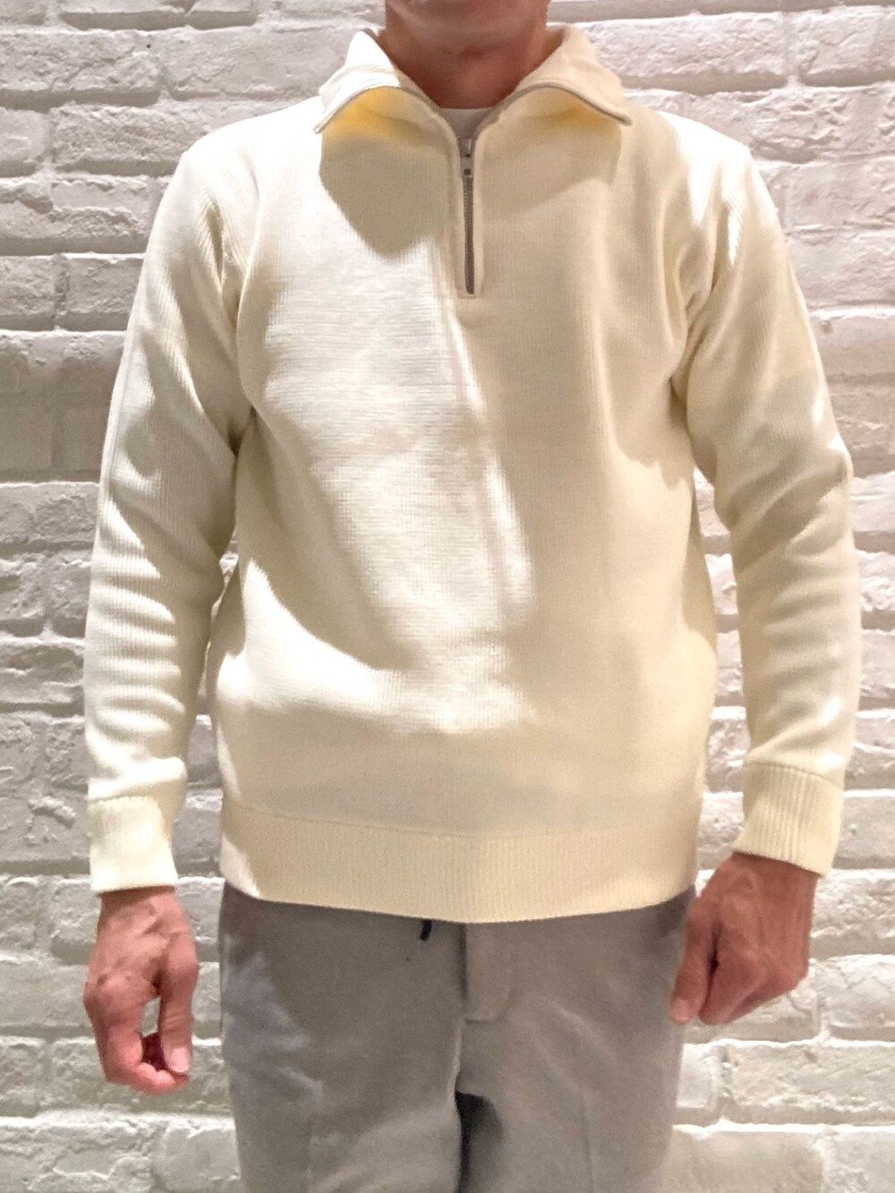 ホワイト系のニット/セーター、ベージュ系のスラックスを着用したメンズの冬コーディネートの4枚目の写真