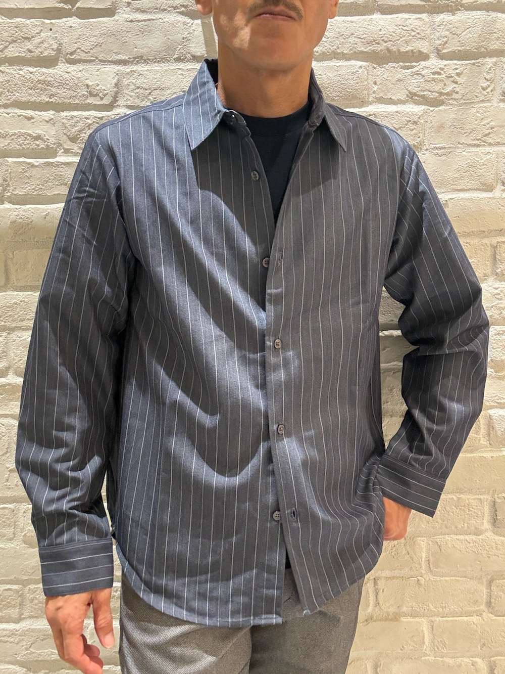 ブルー系のシャツ/ブラウス、ブルー系のTシャツ/カットソー、グレー系のスラックスを着用したメンズの秋コーディネートの2枚目の写真