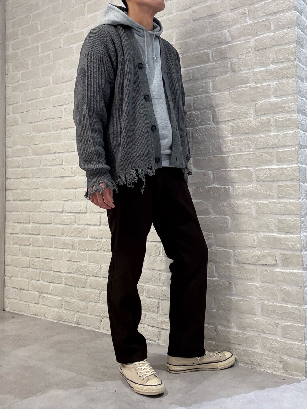 グレー系のカーディガン/ボレロ、グレー系のパーカー、ブラウン系のスラックスを着用したメンズの秋コーディネートの2枚目の写真