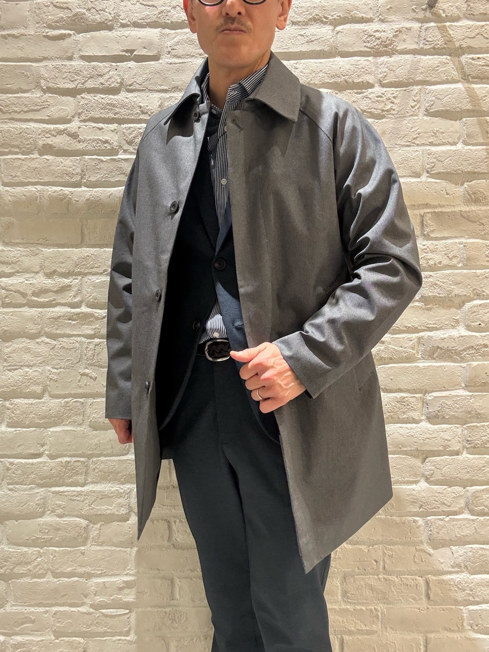 グレー系のステンカラーコート、ブルー系のテーラードジャケット、ブルー系のシャツ/ブラウスを着用したメンズの冬コーディネートの2枚目の写真