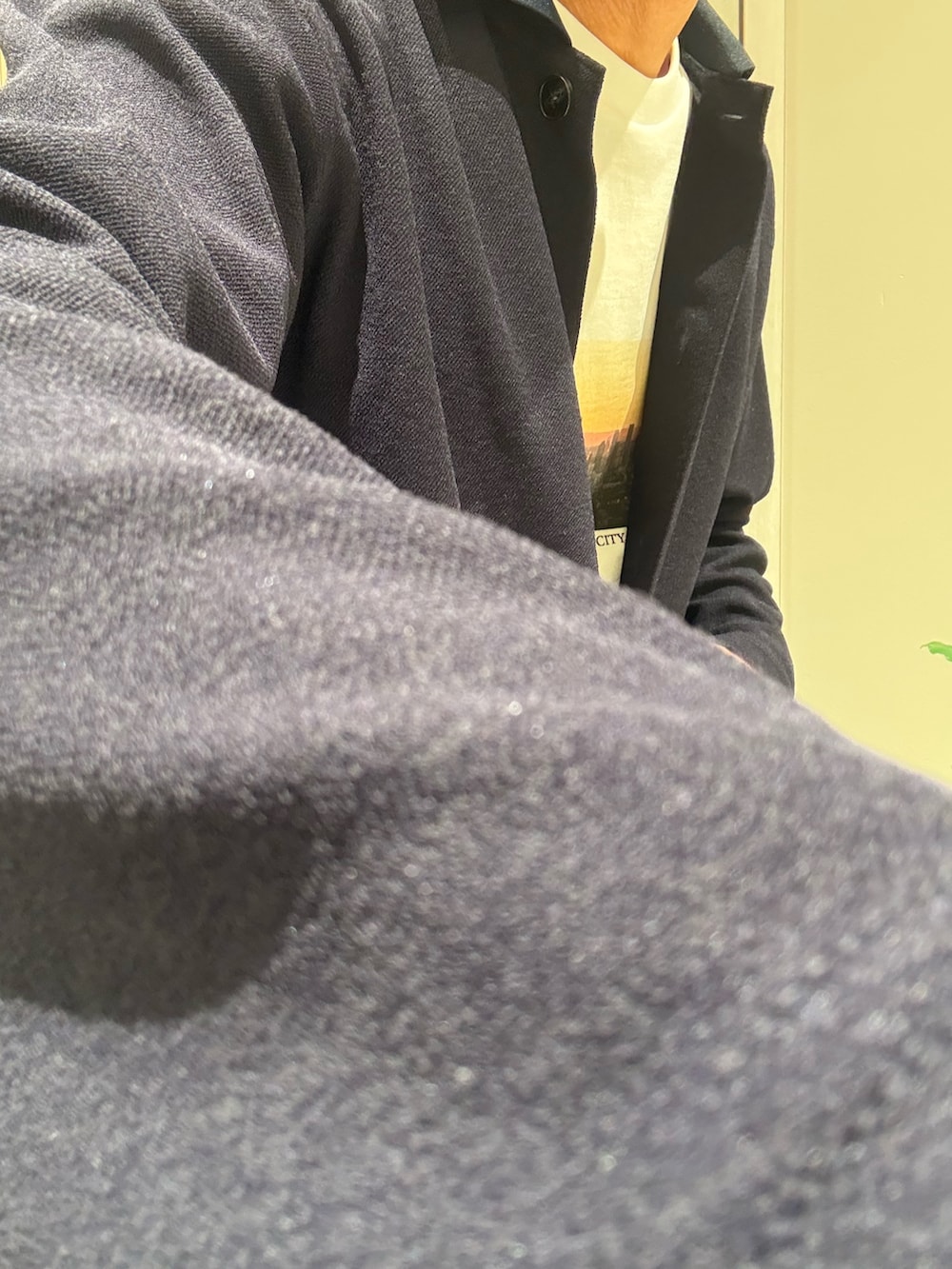 ブルー系のカーディガン/ボレロ、ホワイト系のTシャツ/カットソー、ベージュ系のスラックスを着用したメンズの秋コーディネートの4枚目の写真