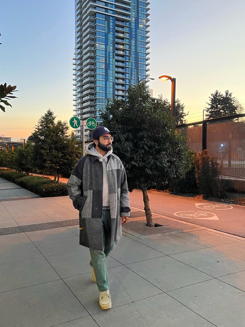 グレー系のステンカラーコート、ブラック系のブーツ、グリーン系のハットを着用したメンズの秋コーディネートの2枚目の写真