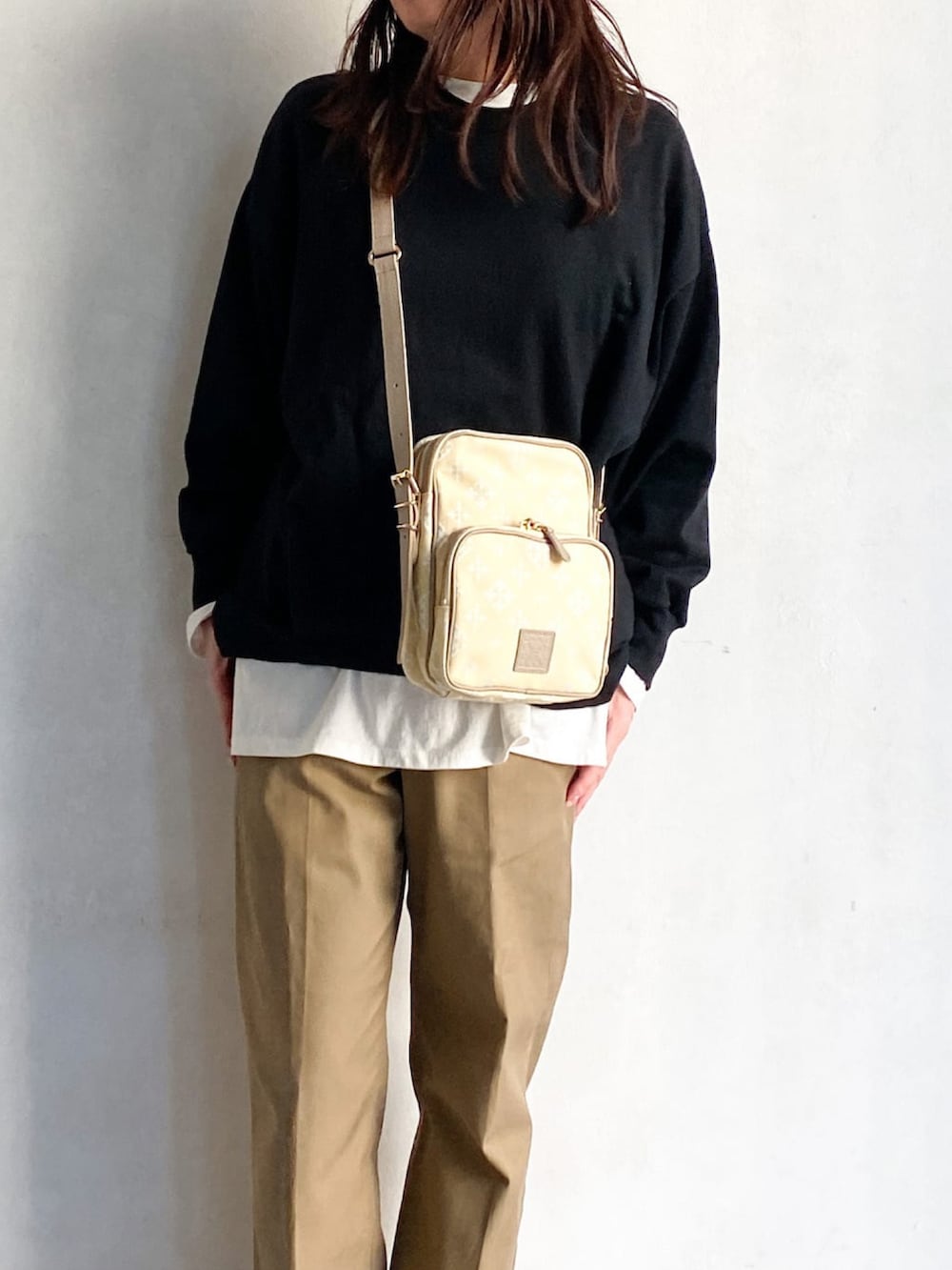 イエロー系のショルダーバッグ、ベージュ系のチノパンツ、ホワイト系のスニーカーを着用したレディースの冬コーディネートの2枚目の写真