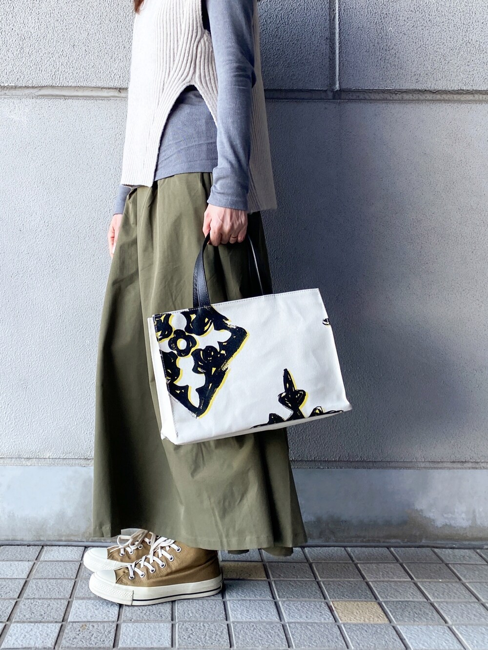 ホワイト系のトートバッグ、ホワイト系のベスト、グレー系のTシャツ/カットソーを着用したレディースの冬コーディネートの2枚目の写真