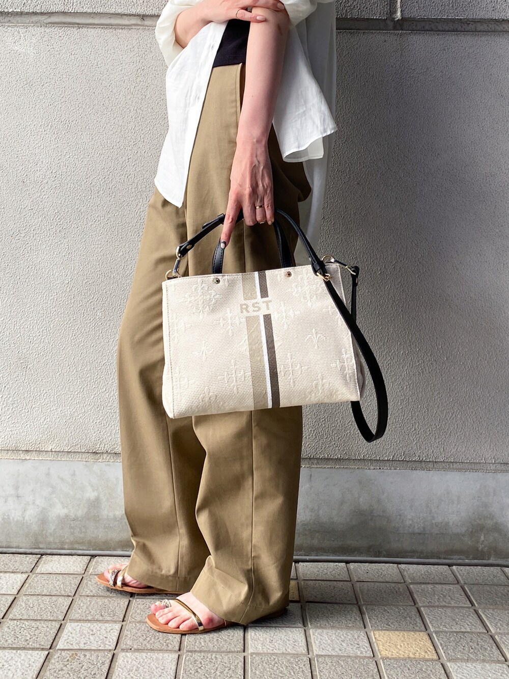 ホワイト系のトートバッグ、ホワイト系のシャツ/ブラウス、ベージュ系のチノパンツを着用したレディースの夏コーディネートの3枚目の写真
